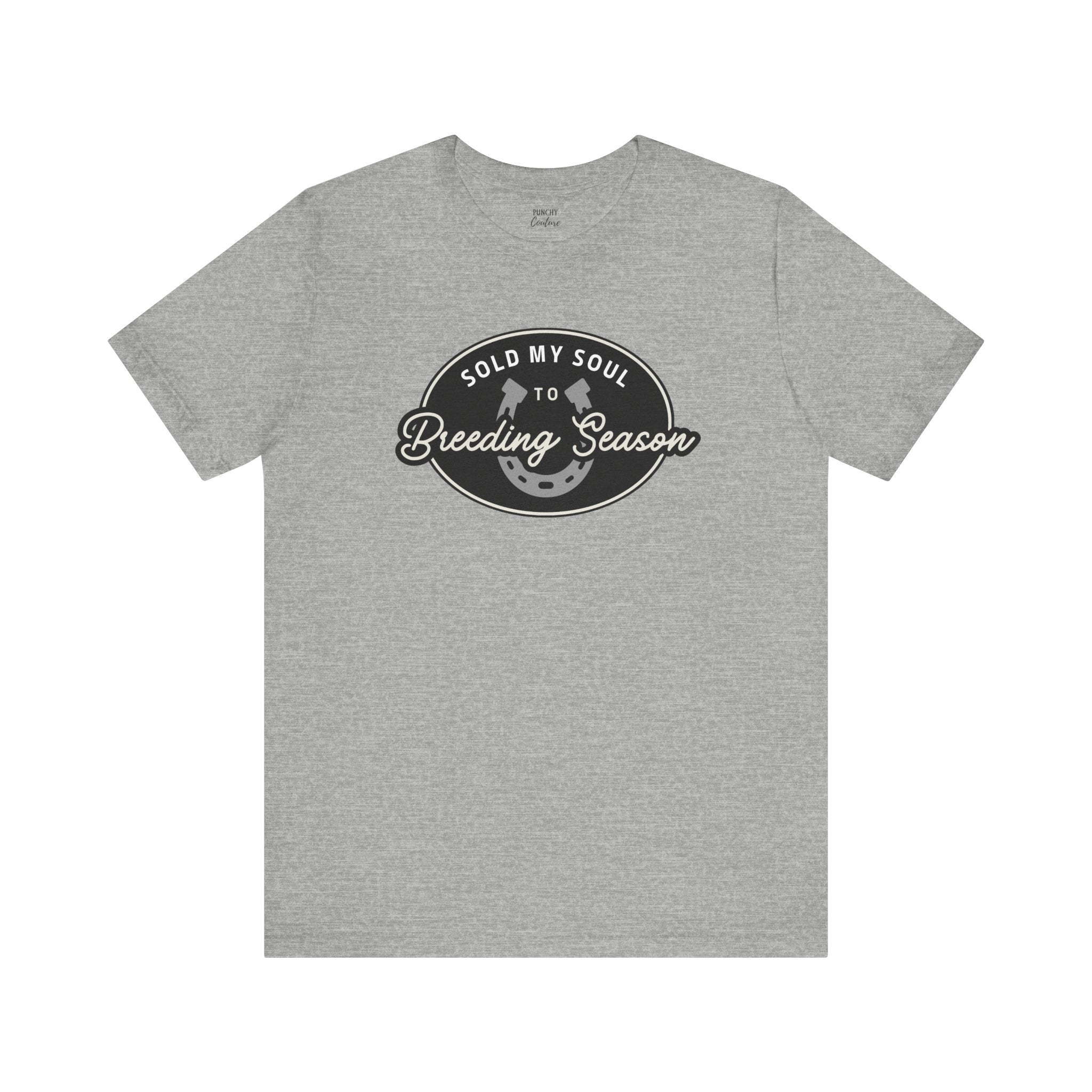 Gray t-shirt with black oval emblem featuring white and gray text “SOLD MY SOUL TO Breeding Season” and graphics of shovels and a horseshoe; humorous Western design with bold contrast.