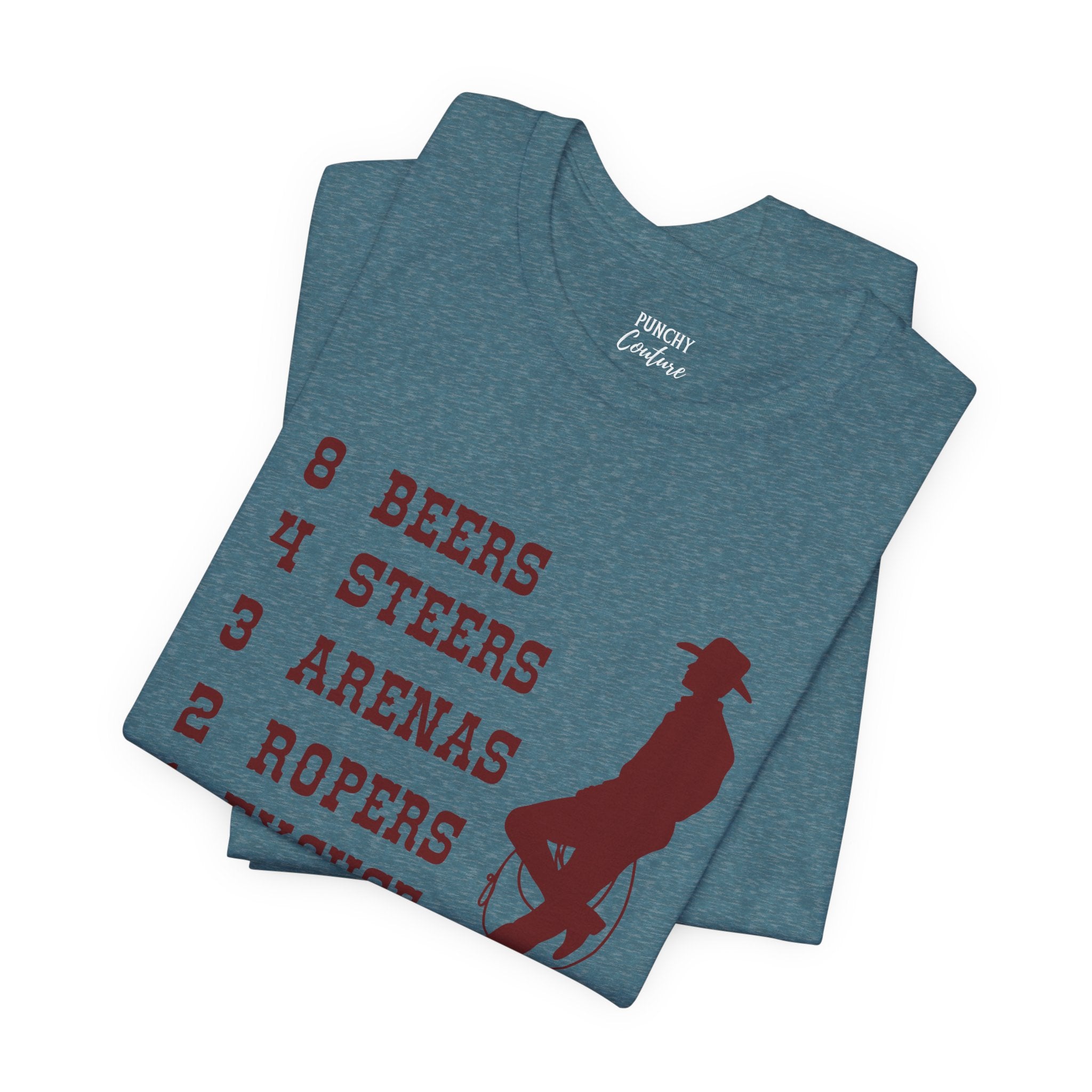 Blue t-shirt with brown cowboy silhouette leaning against a rope and red vertical text reading “8 BEERS, 4 STEERS, 3 ARENAS, 2 ROPERS, 1 EXCUSE”; playful Western graphic tee with rodeo-inspired humor.