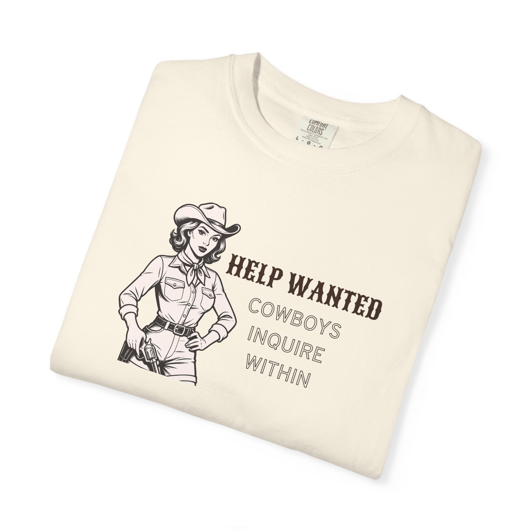 White t-shirt with vintage-style cowboy illustration and bold black text reading “HELP WANTED COWBOYS INQUIRE WITHIN”; Western graphic tee with retro charm and playful attitude.