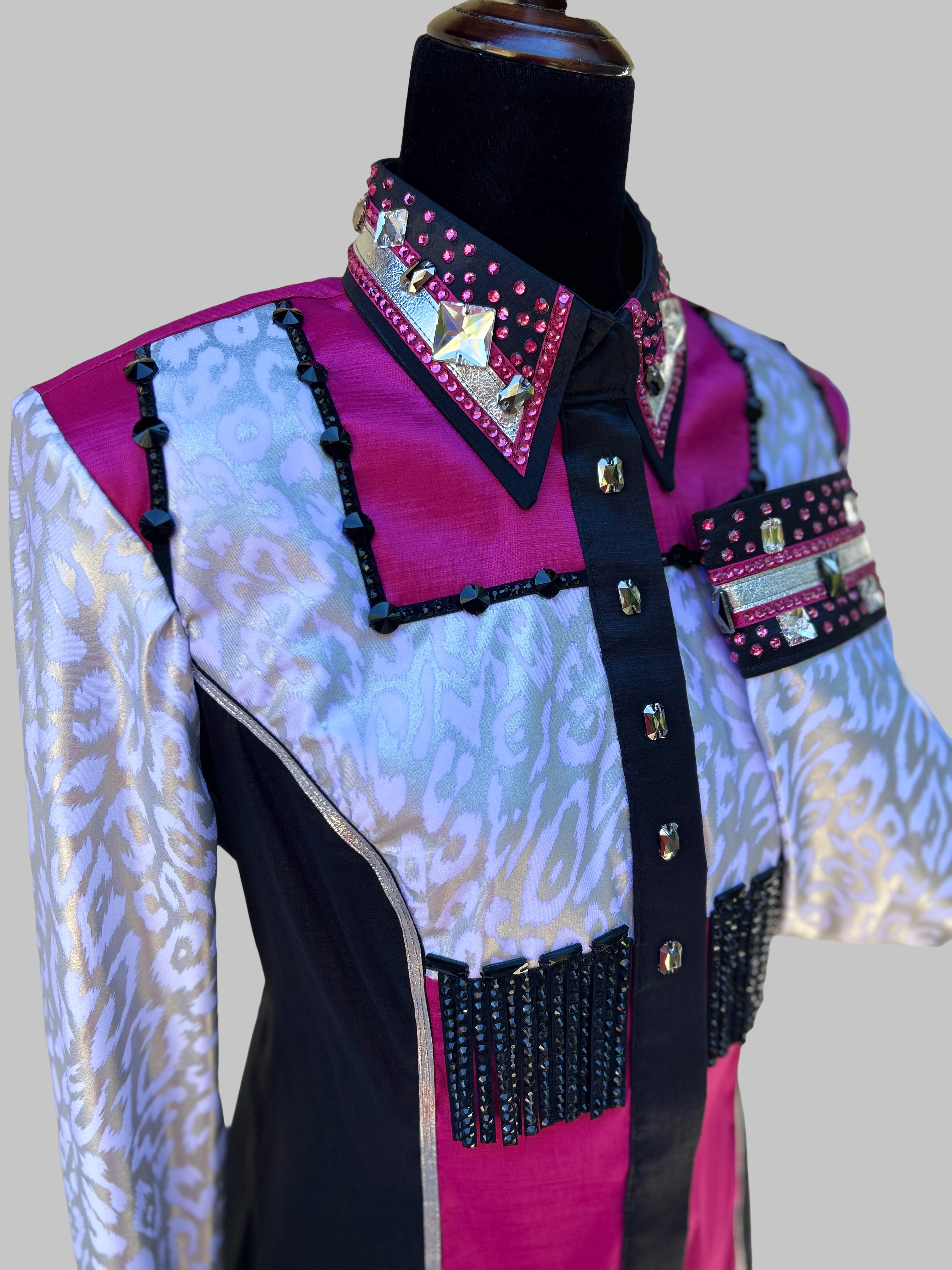 Close up view of Western-style performance shirt in magenta, black, and silver with ornate rhinestones, studs, and beaded accents; dramatic show-day design featuring jacquard textures, barbed embellishments, and couture-level craftsmanship.