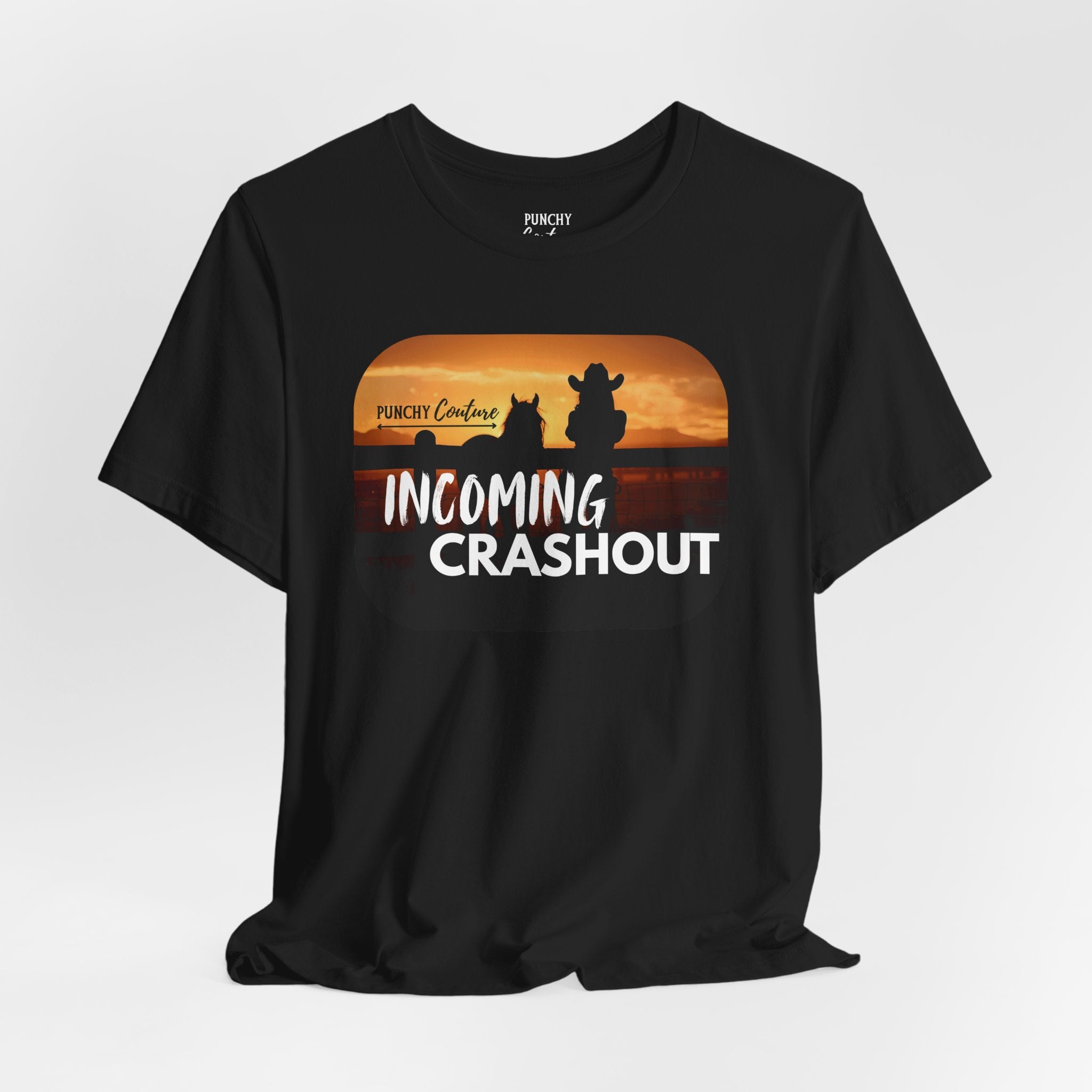 Black t-shirt with sunset graphic featuring silhouettes of two figures, one in a cowboy hat, and bold white text reading "INCOMING CRASHOUT" with "PUNCHY Couture" above; Western-themed tee with relaxed, mythic energy
